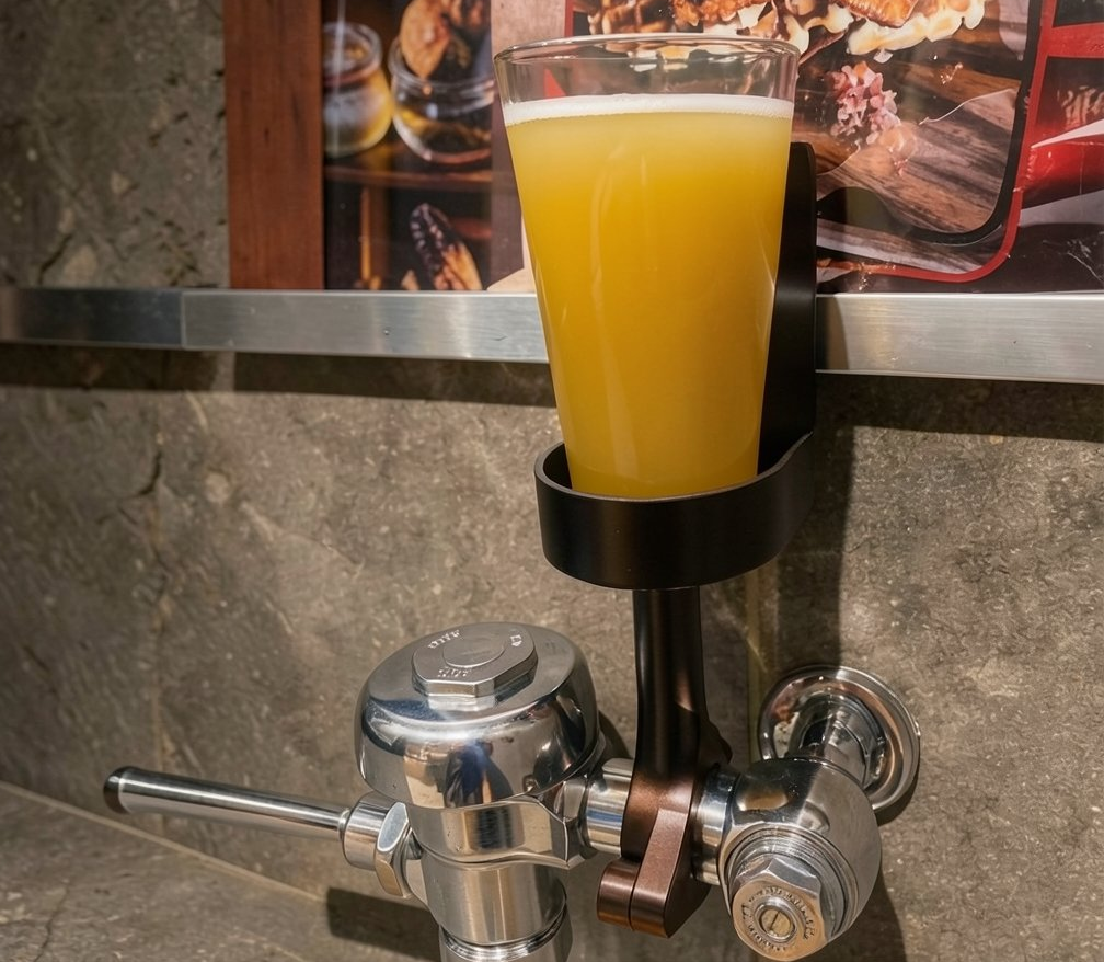 DrinkTight holding a beer above a urinal flush valve